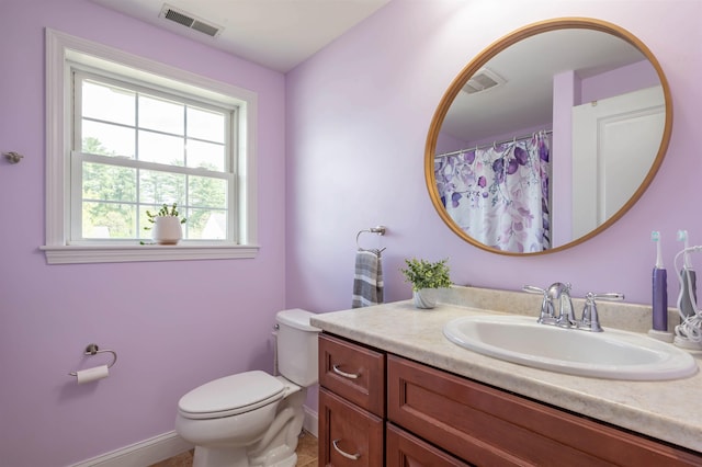full bath with toilet, vanity, and baseboards
