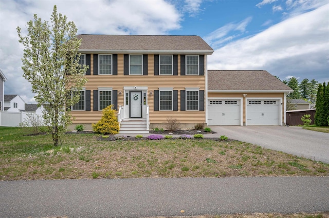 colonial-style house with a garage, driveway, and fence