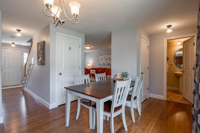 dining area featuring wood finished floors, baseboards, stairs, and a chandelier