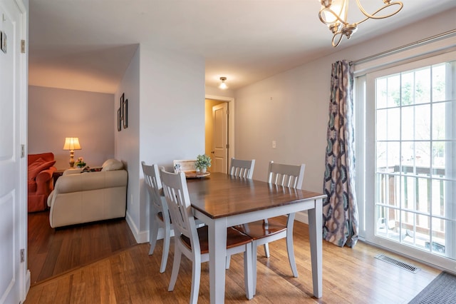 dining space featuring wood finished floors, a chandelier, and baseboards