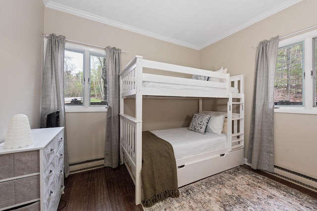 bedroom with a baseboard heating unit, wood finished floors, and crown molding