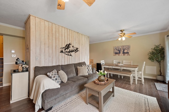 living area featuring a ceiling fan, wood finished floors, crown molding, baseboards, and wood walls