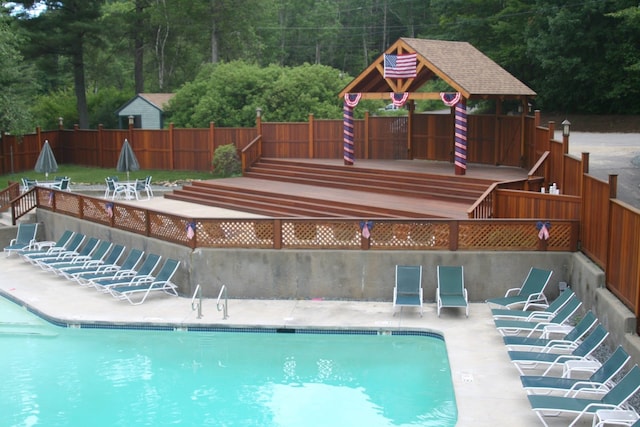community pool with fence, a patio, and a view of trees