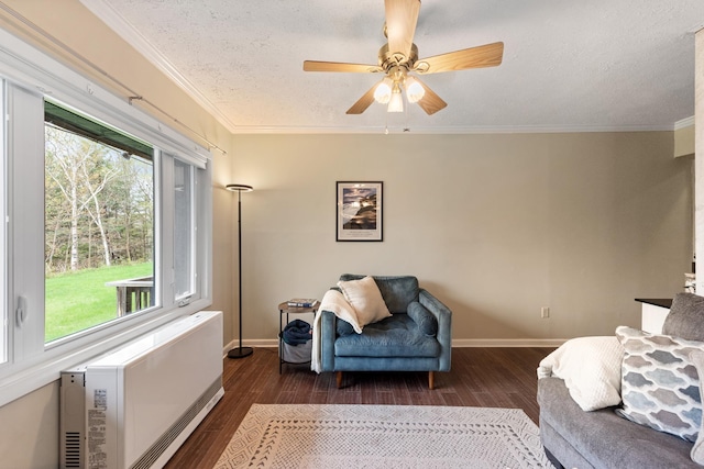 living area featuring plenty of natural light, wood finished floors, a textured ceiling, crown molding, and baseboards