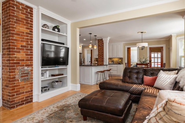 living area with light wood finished floors, built in features, and ornamental molding