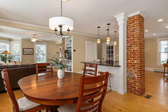 dining space with baseboard heating, light wood-style flooring, a ceiling fan, crown molding, and baseboards