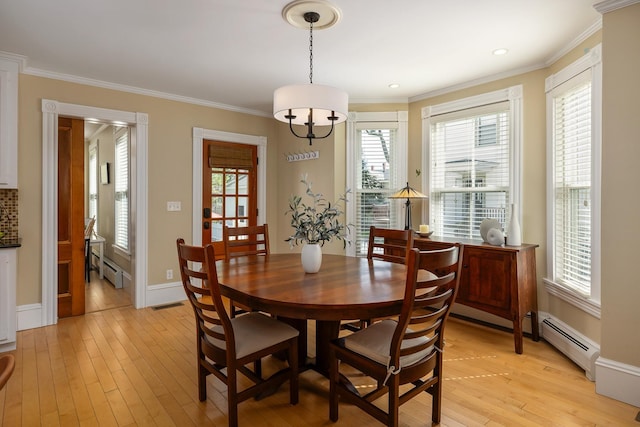 dining space with baseboard heating, plenty of natural light, light wood-style flooring, and crown molding