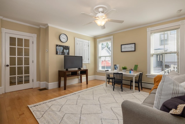 living room with light wood finished floors, a ceiling fan, ornamental molding, baseboards, and a desk