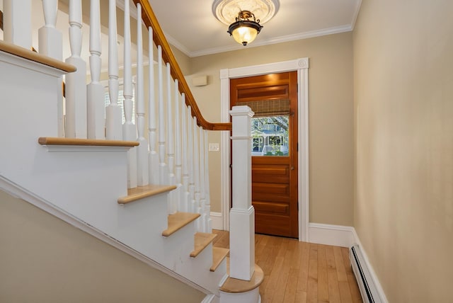 entrance foyer featuring ornamental molding, stairway, light wood finished floors, baseboards, and a baseboard heating unit
