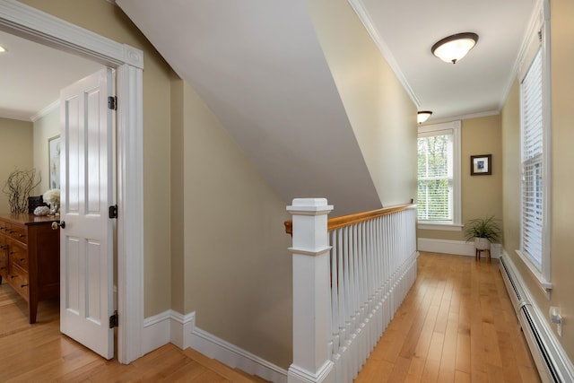 hall with a baseboard radiator, light wood-style floors, an upstairs landing, ornamental molding, and baseboards