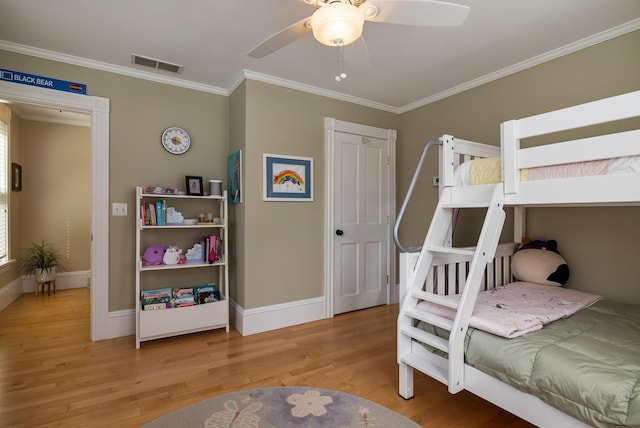 bedroom featuring light wood finished floors, crown molding, baseboards, and ceiling fan