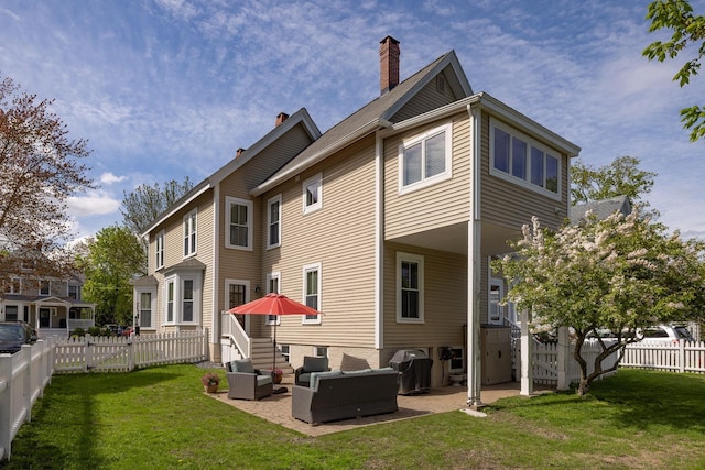 back of property featuring outdoor lounge area, a patio, a chimney, and a gate