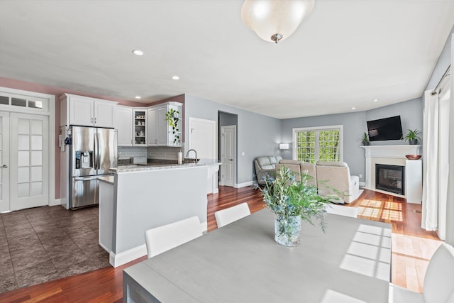 dining room with a glass covered fireplace, dark wood-type flooring, baseboards, and recessed lighting
