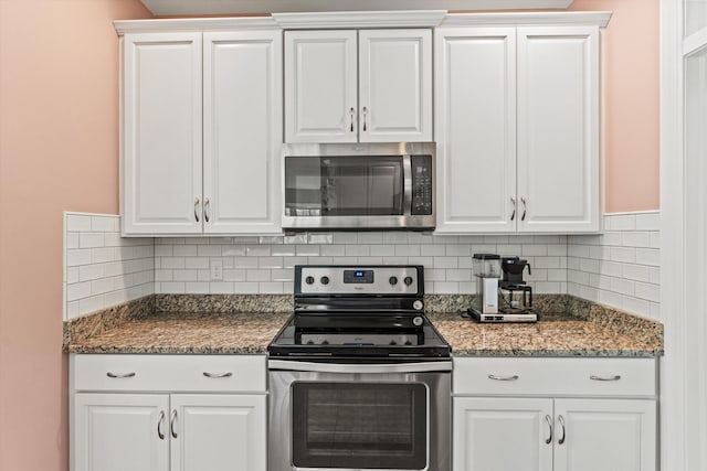 kitchen with appliances with stainless steel finishes, white cabinets, backsplash, and dark stone counters