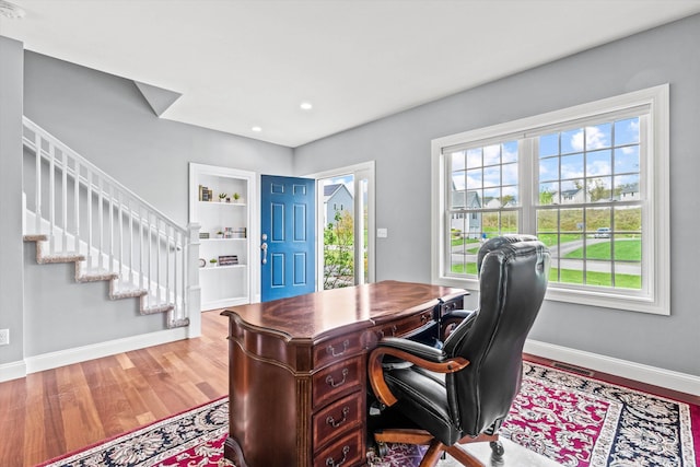 home office featuring baseboards, wood finished floors, built in features, and recessed lighting