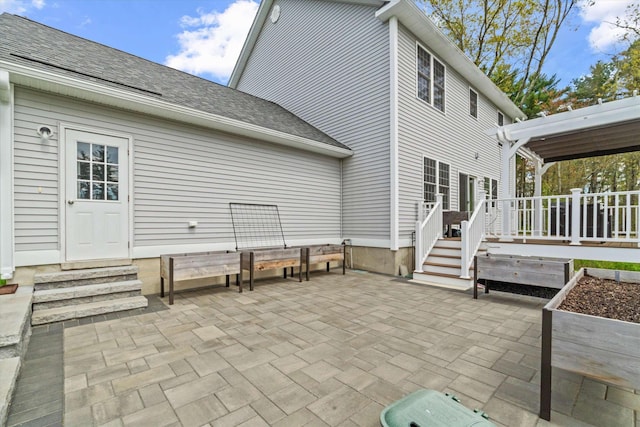 back of property featuring a patio area, entry steps, a deck, and a shingled roof