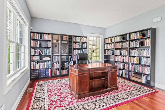 home office with bookshelves, wood finished floors, and baseboards
