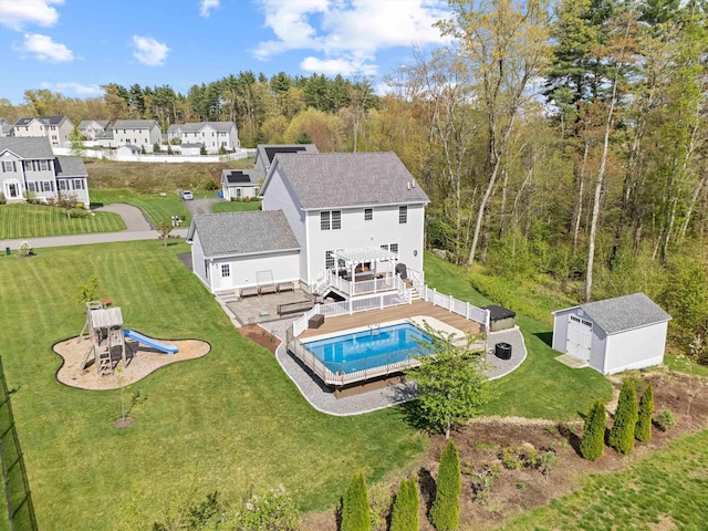 outdoor pool with an outbuilding, a yard, a deck, and a playground