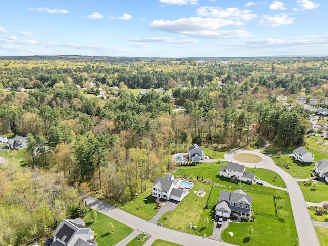 aerial view of property and surrounding area featuring a heavily wooded area and nearby suburban area