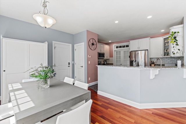 dining room featuring light wood finished floors, recessed lighting, and baseboards