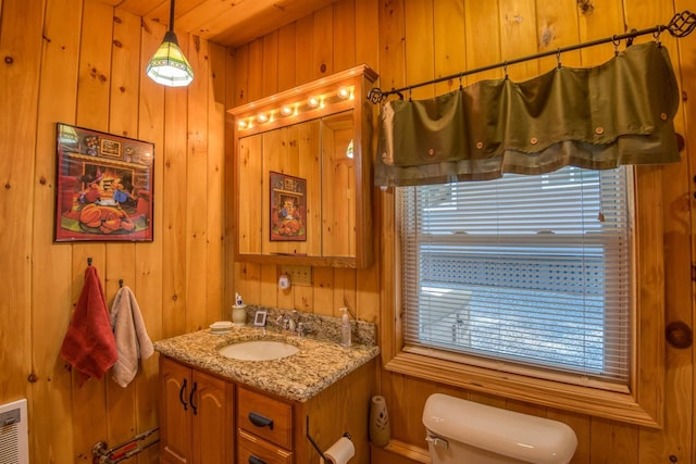 half bathroom with toilet, wooden walls, and vanity