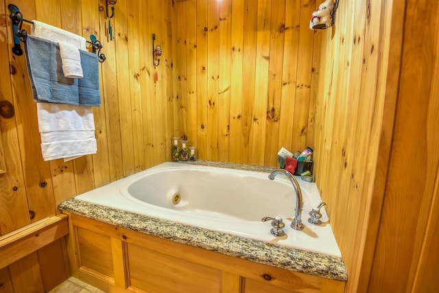 bathroom featuring a bath and wood walls
