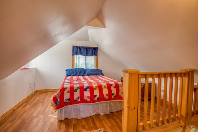 bedroom featuring wood finished floors, baseboards, and vaulted ceiling