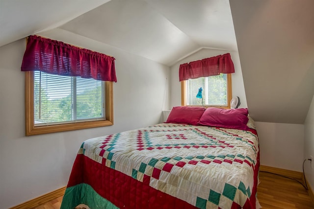 bedroom with vaulted ceiling, baseboards, and wood finished floors