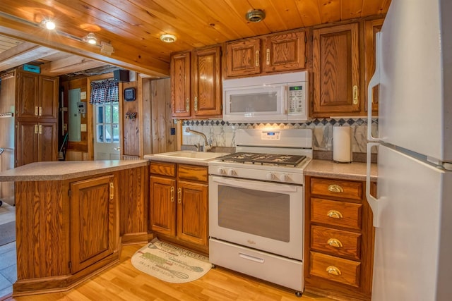 kitchen with white appliances, brown cabinets, light wood-type flooring, light countertops, and a peninsula