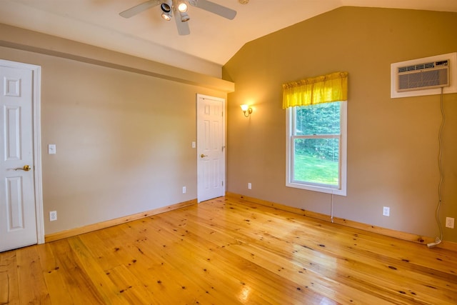 unfurnished room with lofted ceiling, a wall mounted air conditioner, ceiling fan, wood-type flooring, and baseboards