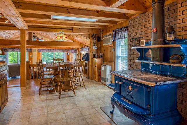 dining area with beam ceiling, a wood stove, wooden walls, a wall mounted air conditioner, and brick wall