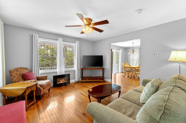 108 Brenner Dr, Conway, NH 03818 - living area with wood-type flooring, ceiling fan, a warm lit fireplace, and a chandelier