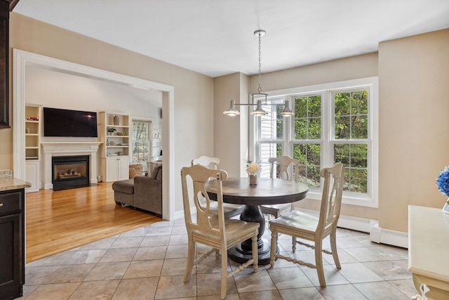 dining space with light tile patterned flooring, a fireplace with flush hearth, and baseboards