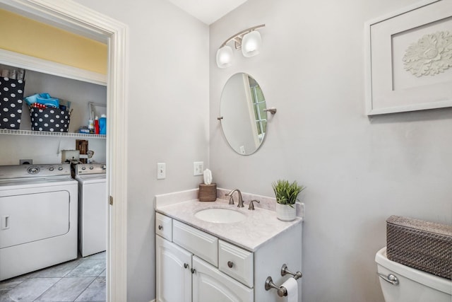 half bathroom featuring separate washer and dryer, toilet, tile patterned floors, and vanity