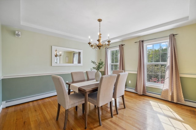 dining room with a chandelier, a raised ceiling, a baseboard radiator, and light wood-style floors