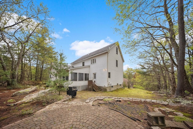 rear view of property featuring a sunroom and roof with shingles