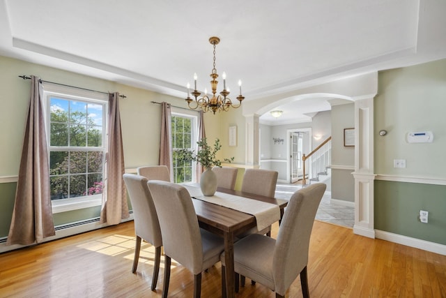 dining area with ornate columns, a chandelier, arched walkways, and light wood-type flooring