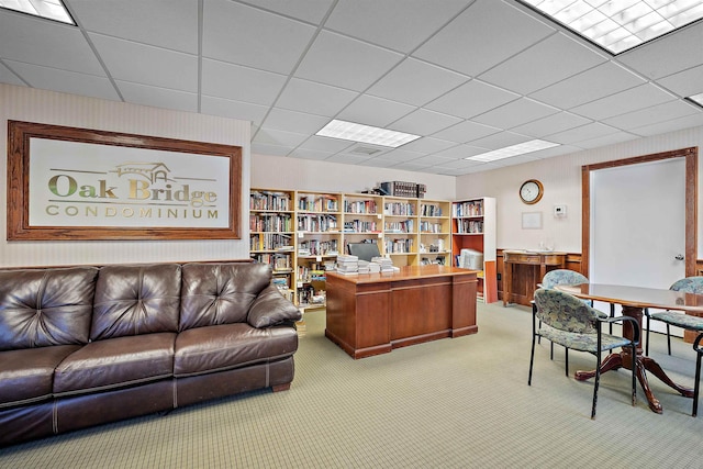 carpeted office featuring a paneled ceiling and wood walls