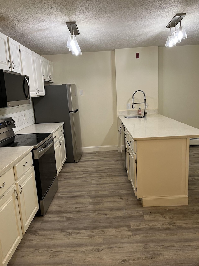 kitchen with stainless steel appliances, a sink, a textured ceiling, a peninsula, and light countertops