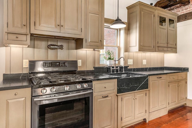 kitchen with gas range, dark countertops, a sink, dark wood-style floors, and hanging light fixtures