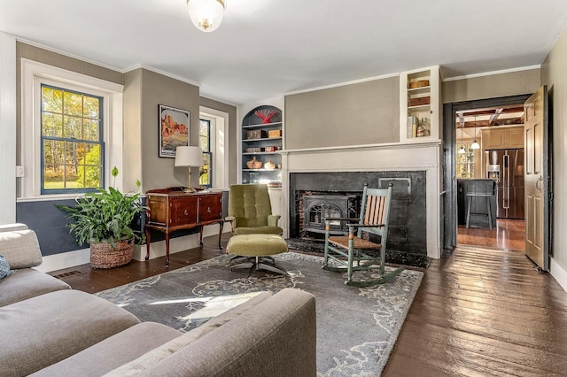 living area with hardwood / wood-style flooring, baseboards, ornamental molding, and built in shelves