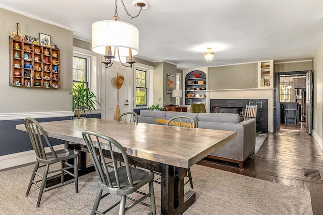dining area featuring crown molding, hardwood / wood-style flooring, a fireplace, and baseboards