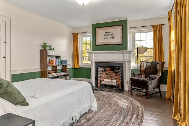 bedroom with ornamental molding, wood finished floors, and a fireplace