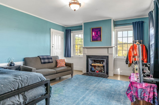 living area featuring healthy amount of natural light, a fireplace with flush hearth, crown molding, and wood finished floors