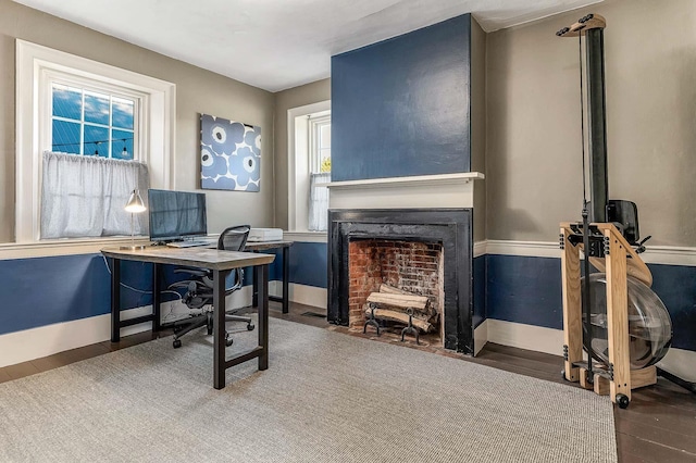 office featuring wood finished floors, a fireplace with flush hearth, and baseboards