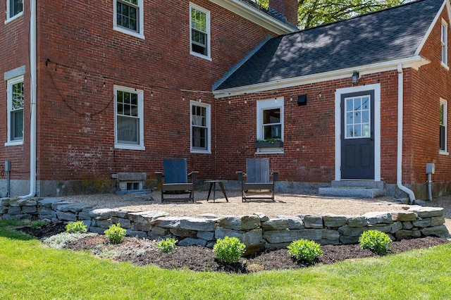 back of house featuring brick siding, a chimney, and roof with shingles