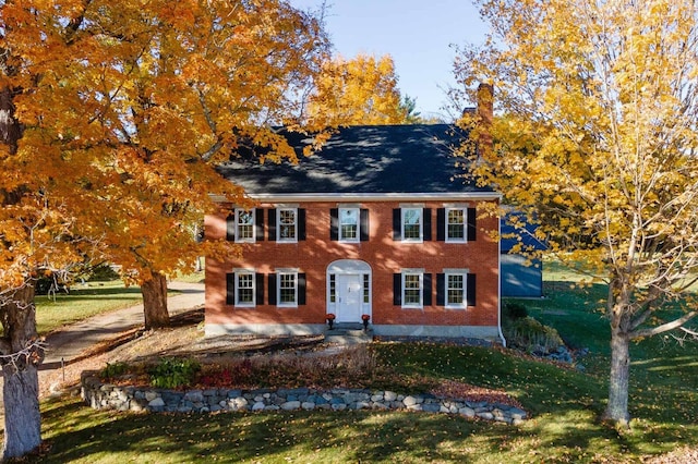 colonial inspired home with a front lawn and a chimney