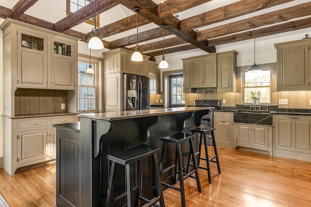 kitchen featuring refrigerator with ice dispenser, a sink, light wood-style floors, a kitchen island, and beam ceiling