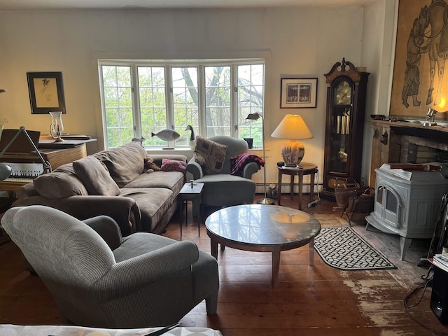 living room with a baseboard radiator, a wood stove, and hardwood / wood-style floors