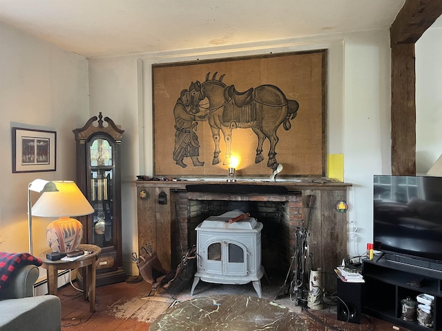 living area featuring a wood stove, wood finished floors, and a baseboard heating unit